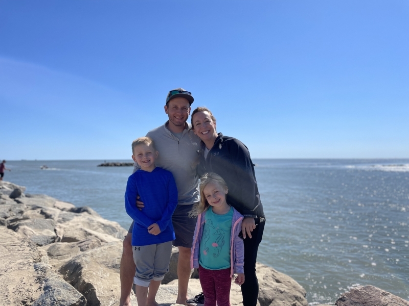 Dan Robb with his wife and two kids posing in front of ocean. 
